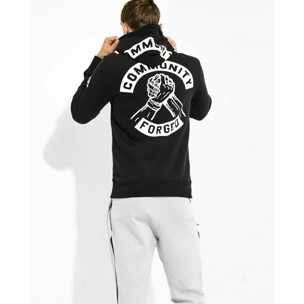 Ragazzo di spalle che indossa una felpa con cappuccio nera con la scritta Community Forged e due mani che si intrecciano